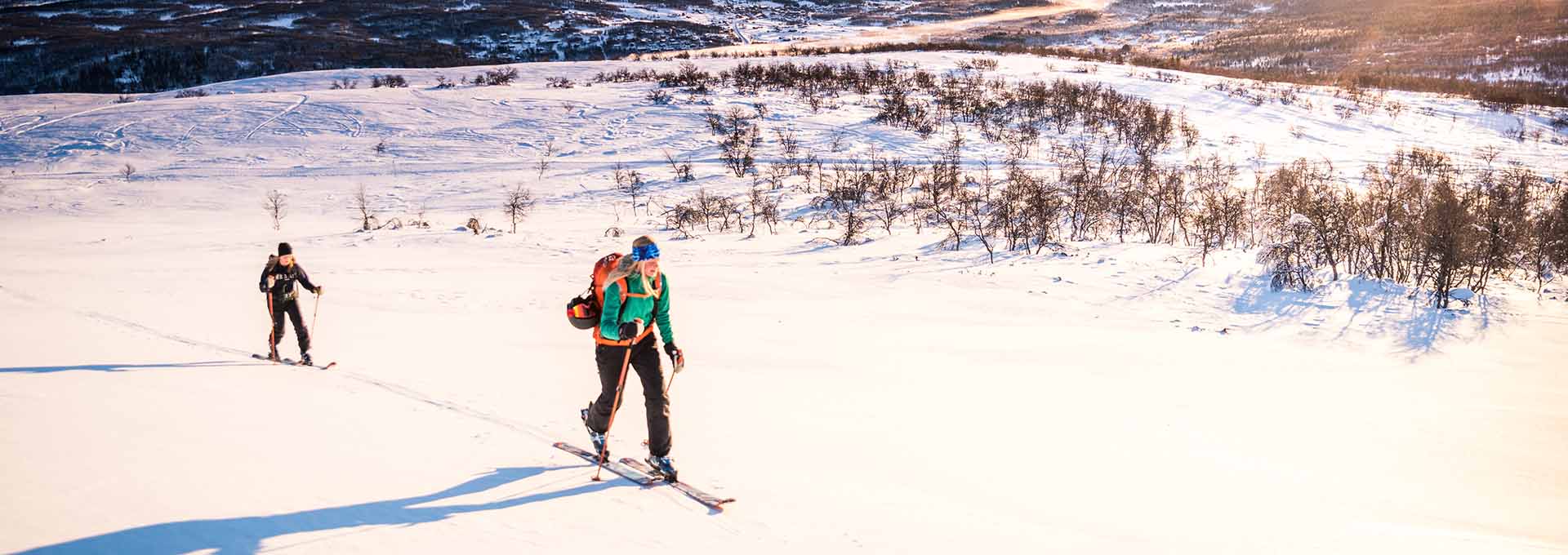två personer på väg uppför berget med topptursutrustning